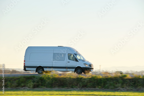 Small cargo van driving on highway hauling goods. Delivery transportation and logistics concept