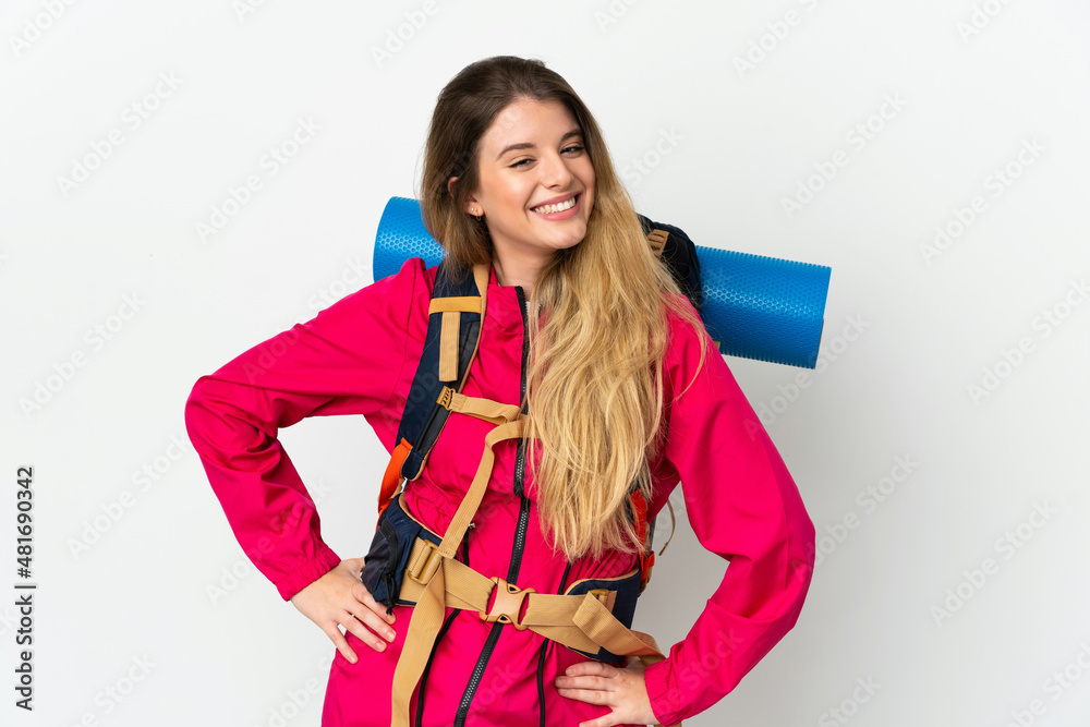 Young mountaineer woman with a big backpack over isolated background posing with arms at hip and smiling Young mountaineer woman with a big backpack over isolated background posing with arms at hip and smiling