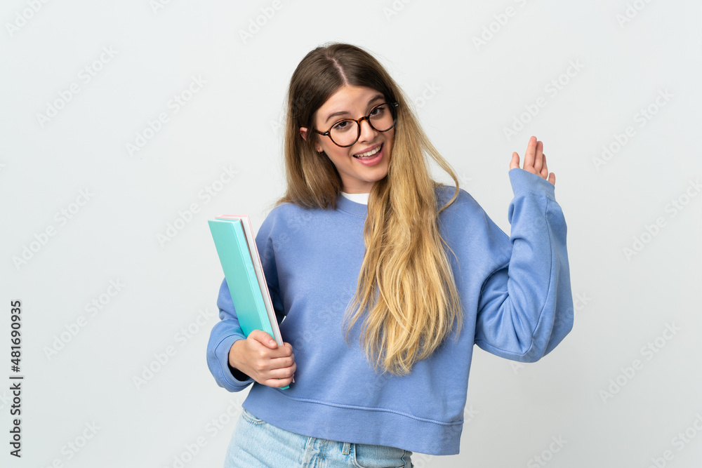 Young blonde student woman isolated on white background saluting with hand with happy expression Young blonde student woman isolated on white background saluting with hand with happy expression