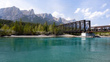 Canmore Engine Bridge in summer with moutains in the background and blue glacial reiver in the foreground, Alberta, Canada.