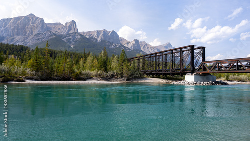 Canmore Engine Bridge in summer with moutains in the background and blue glacial reiver in the foreground, Alberta, Canada.