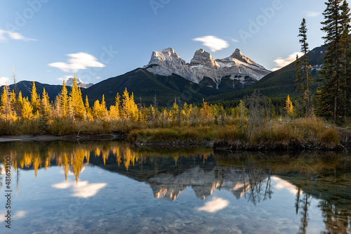 Sunset view in Canadian Rockies with Three Sisters peaks reflecting in water, Canmore, Alberta, Canada. photo