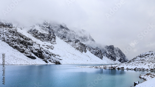 Winter panoramic view of vibrant blue glacial Wedgemount Lake, snow covered mountains in the background, British Columbia, Canada.