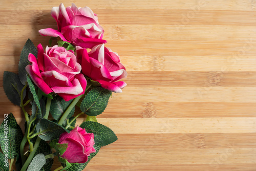 Bouquet of pink plastic roses on a wooden table