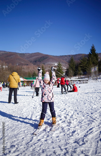 girl on skis in winter things. Snow outside. hands up like a winner