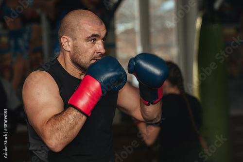 A male athlete of a strong physique, a boxer stands in a boxing stance and is ready to strike. He is wearing boxing gloves