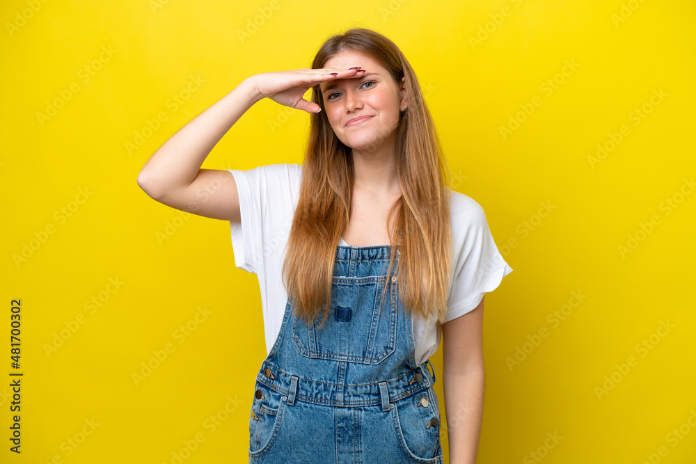 Young caucasian woman isolated on yellow background looking far away with hand to look something Young caucasian woman isolated on yellow background looking far away with hand to look something