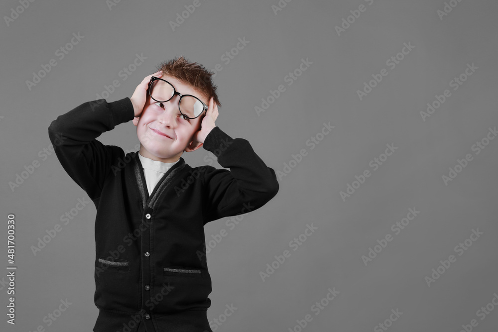 Little cute boy with glasses is smiling and having fun isolated on grey background. happy childhood. copy space