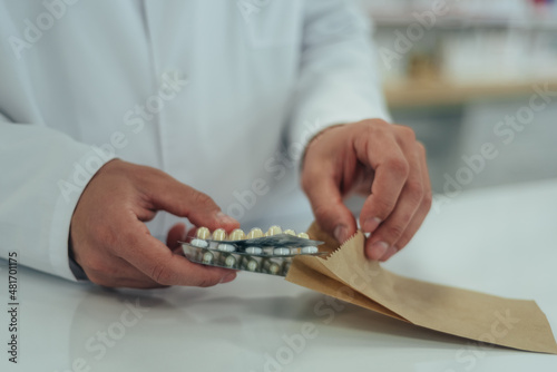 Hands of a pharmacist packing medications in a paper bag