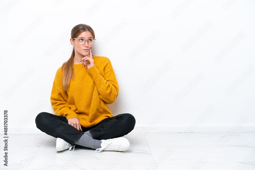 Young caucasian woman sitting on the floor isolated on white background thinking an idea while looking up Young caucasian woman sitting on the floor isolated on white background thinking an idea while looking up
