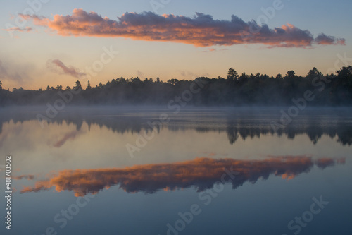clouds reflecting on calm water morning mist hovering over lake at sunrise early morning fog or mist trees forest or woods reflecting in tranquil calming lake water blue sky purple clouds horizontal © Shawn Hamilton CLiX 
