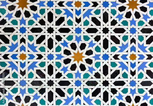 Old Islamic tiles (also known as zellige or azulejos) with traditional geometric patterns decorating a wall of the Nasrid Palaces inside the Alhambra. Granada, Andalusia, Spain. photo