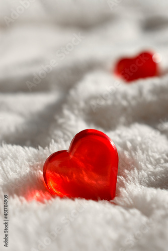 Close up red glass heart on white fur background. Minimalist greeting mock concept for Valentines day  Mothers day  romantic data or wedding. Trendy sunlight still life. Vertical shot.