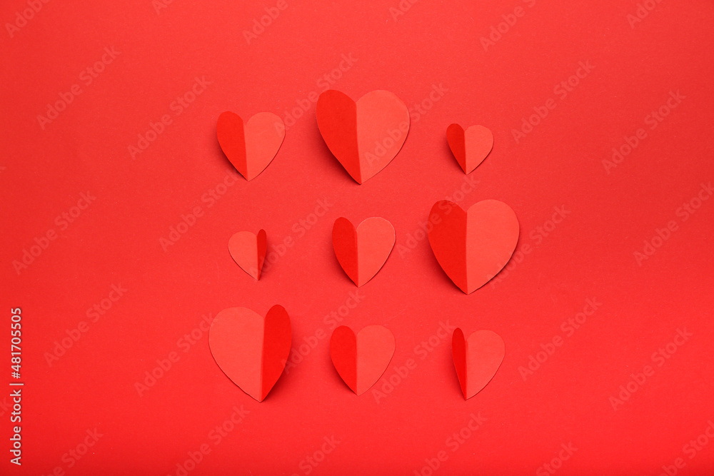 Composition for Valentine's Day February 14. Red background and red hearts cut out of paper. Postcard. Flat lay, top view.