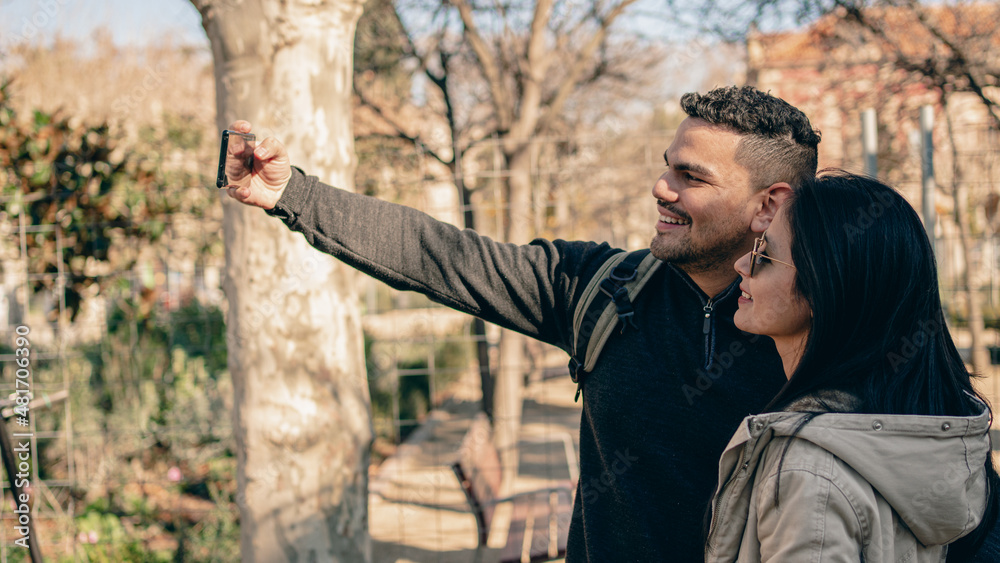 man and woman taking a selfie in a park man and woman taking a selfie in a park
