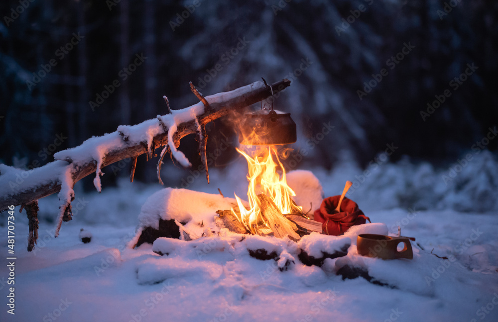 Making coffee over a campfire in a snow-covered forest landscape - obrazy, fototapety, plakaty 