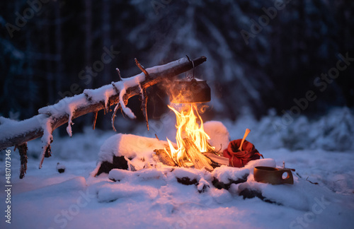 Making coffee over a campfire in a snow-covered forest landscape