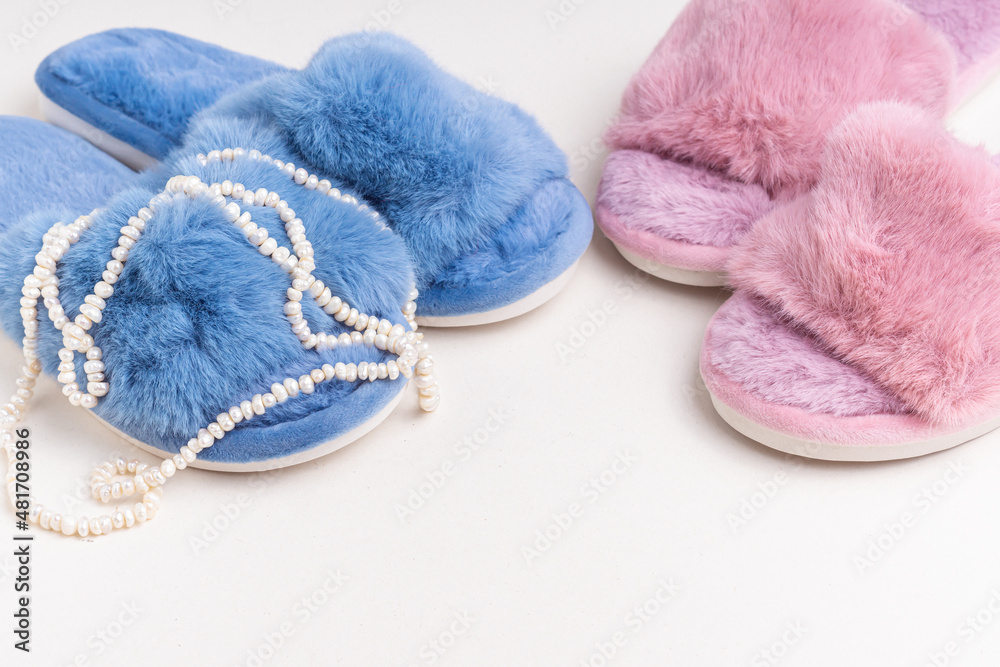 Blue and pink women's home slippers and pearl necklace. Comfortable shoes for home. Space for text