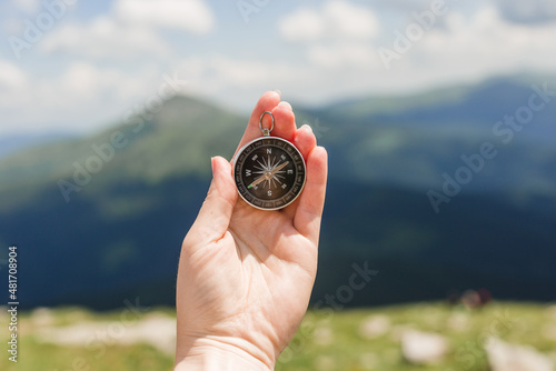Woman holding a compass in hand on nature background, ready to travel, keep calm. Tourism, traveling, hiking and healthy lifestyle concept.