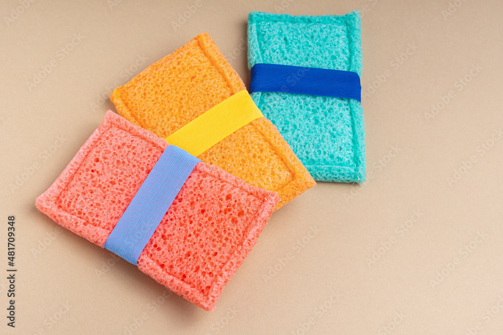 Three multi colored washcloth sponges on beige background. Space for text. Top view. Washcloths massage for the body Three multi colored washcloth sponges on beige background. Space for text. Top view. Washcloths massage for the body