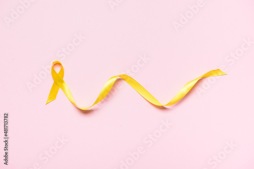 Golden awareness ribbon on color background. International Childhood Cancer Day