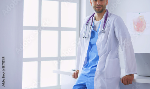 Young and confident male doctor portrait standing in medical office. photo