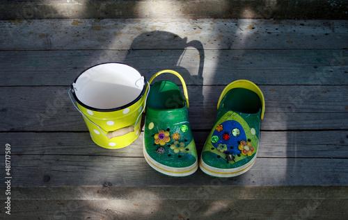 Fototapeta Green clogs on a wooden porch