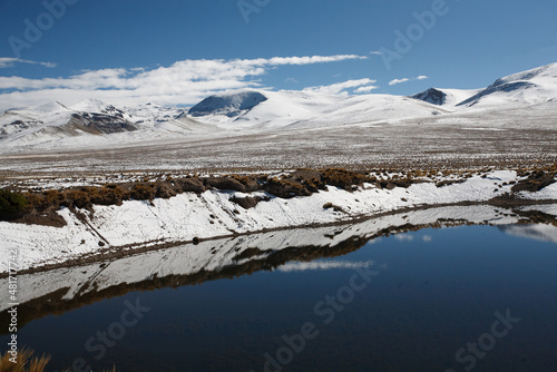 Landscape of the puna of Peru, snowy, with a lagoon and ichu plants photo