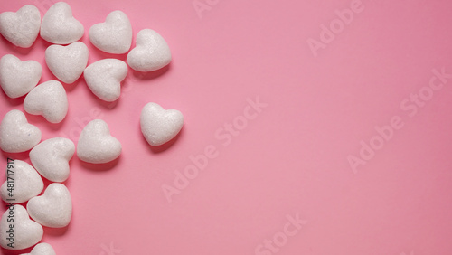 Creative layout made with little white hearts on the side of a pink background. Minimal romantic. Copy space. Valentine's Day Mothers Day concept.