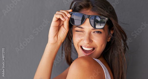 Hey you.... Shot of an attractive young woman winking at the camera while holding up her sunglasses. photo