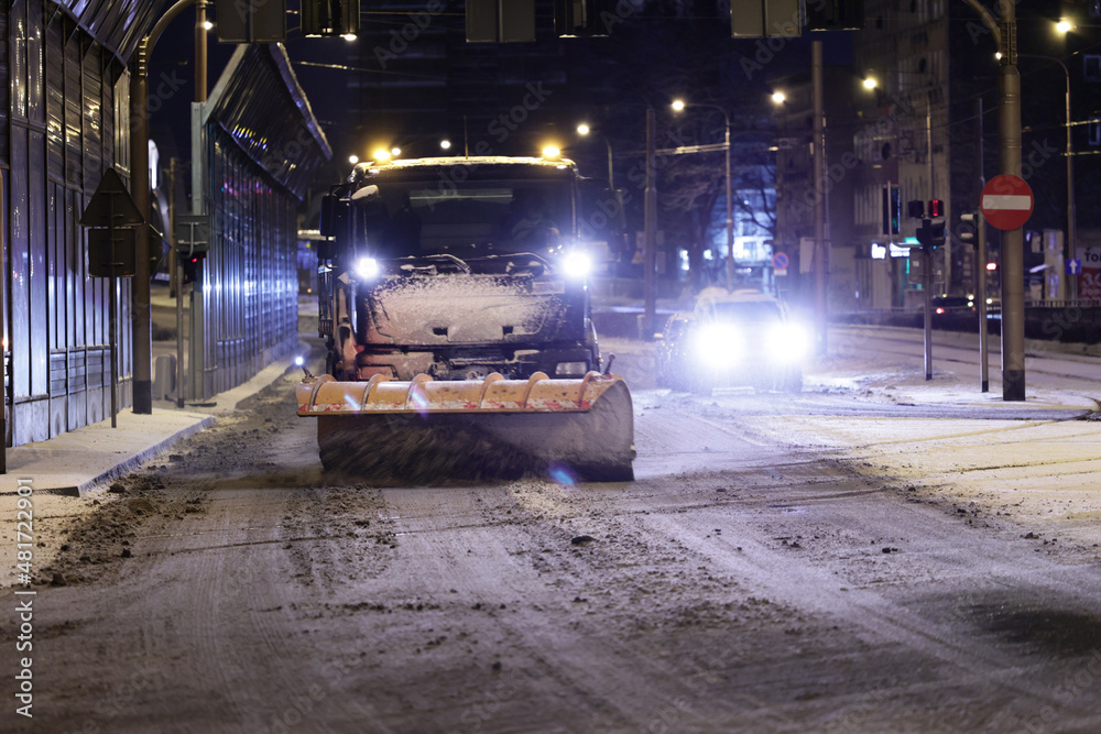 Pojazdy pług i piaskarka na drodze po nocnych opadach śniegu w mieście i ruch pojazdów.  - obrazy, fototapety, plakaty 