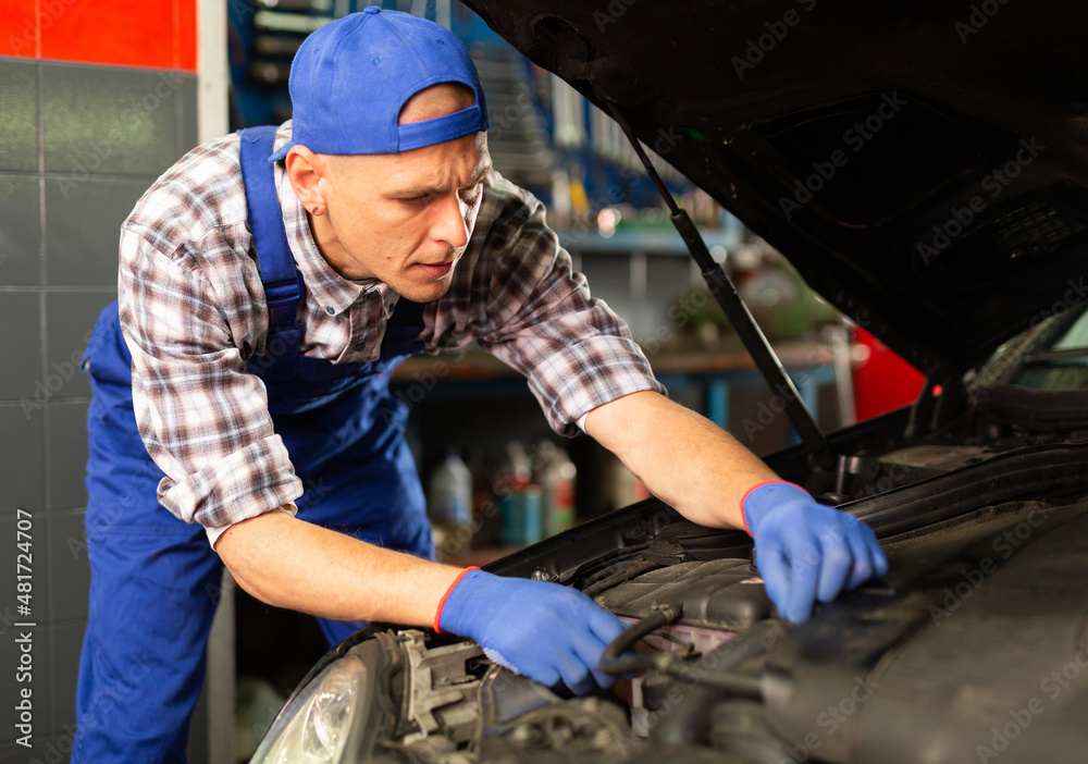 Positive man car mechanician repairing car in auto repair shop