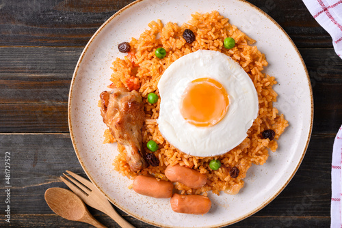 Fried rice with chicken, sausage and fried egg on wooden background, Table top view