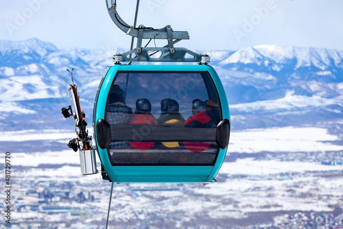 Cable car cabin full of skiers and snowboarders against the snow-covered mountains