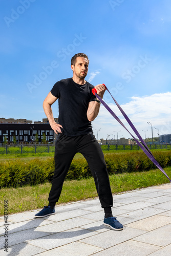 Young man having resistance band workout outdoor