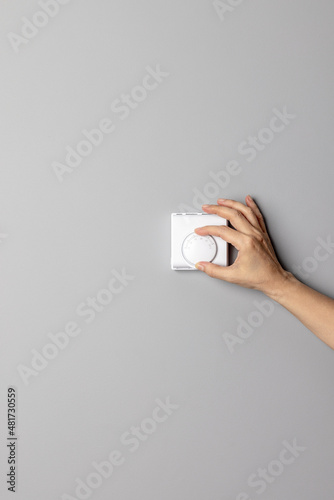 Woman's hand adjusting Turning On-Off wall temperature regulator control button