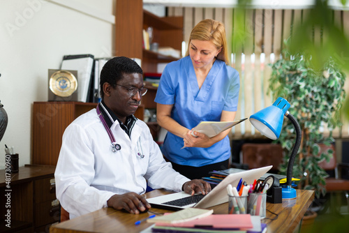 Male doctor and female nurse having productive day in office