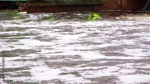 A bird flies over the dam, foam in the water photo