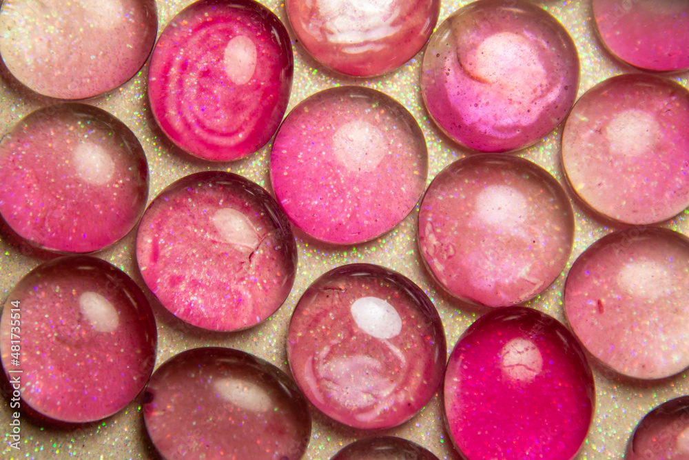 Macro abstract texture background of bright pink and light green color dragon tear glass beads on a white glittery surface Macro abstract texture background of bright pink and light green color dragon tear glass beads on a white glittery surface