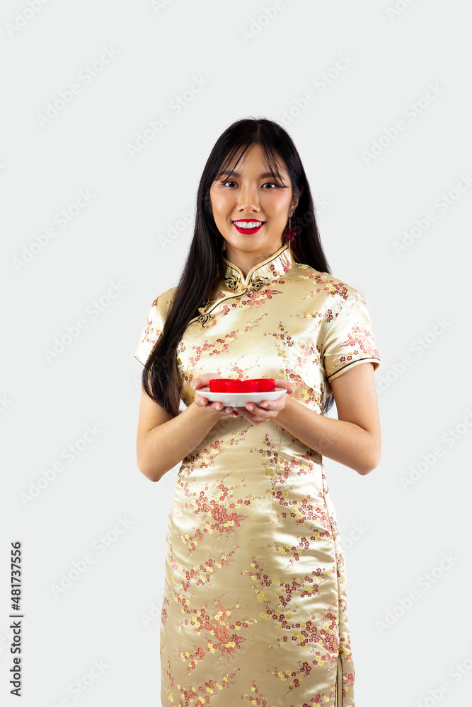 Chinese new year woman concept, isolated asian woman wearing gold dress Cheongsam holding a plate of teas Chinese new year woman concept, isolated asian woman wearing gold dress Cheongsam holding a plate of teas