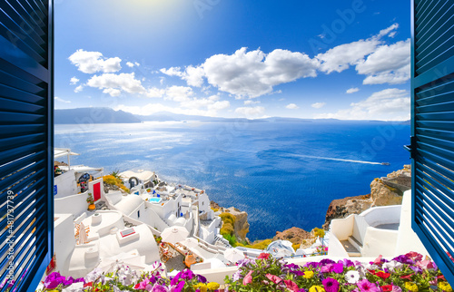 View through an open window with shutters of the caldera, sea and white village of Oia on the island of Santorini, Greece.