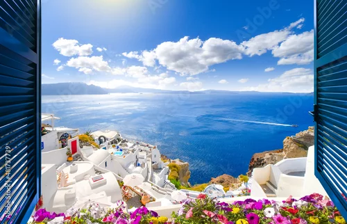 Fototapeta View through an open window with shutters of the caldera, sea and white village of Oia on the island of Santorini, Greece.