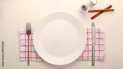 Empty white ceramic plate mockup with cutlery.