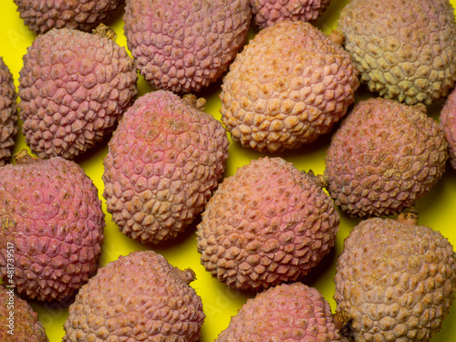 Lychee on the table. Chinese plum on a yellow background. Ripe fruit from Asia.