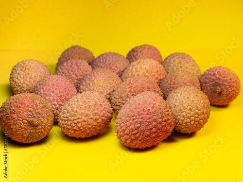 Lychee on the table. Chinese plum on a yellow background. Ripe fruit from Asia.
