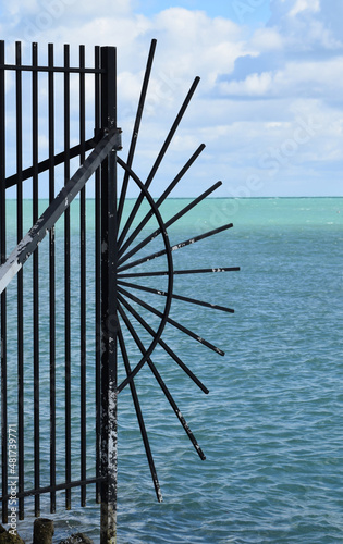 Rusty fence with metal bursts in Cape Florida, with the ocean in the background.