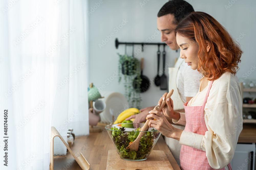 Asian beautiful woman cook green salad with husband in kitchen at home. Asian beautiful woman cook green salad with husband in kitchen at home.