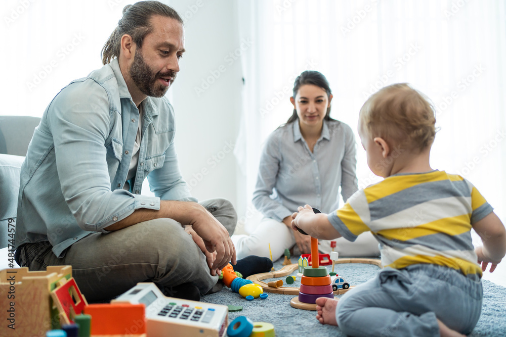 Caucasian happy loving parent play with baby toddler in living room. Caucasian happy loving parent play with baby toddler in living room.