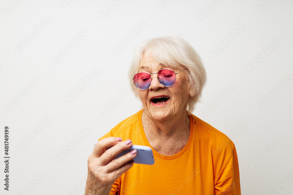 elderly woman in a yellow t-shirt posing communication by phone close-up emotions