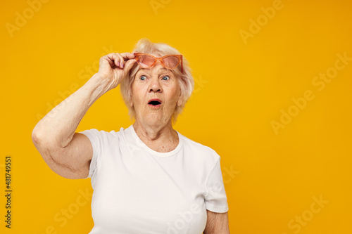 Portrait of an old friendly woman in a white t-shirt wears glasses isolated background